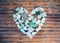 Seashore glass pebble heart on wooden background. Sugar glass mosaic for Valentine`s Day.