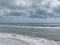 Seashore of Marina di Pisa beach with sailboats on the horizon in a cloudy day at summer. Tuscany, Italy