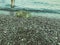 Seashore with water and sand. a girl in protective slippers walks along the stones near the shore. tidal bore. wet stones. waves