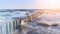 Seaside of Baltic Sea in Poland. Seagulls over stormy sea, with waves hiting wooden poles. Windy day with blue sky.