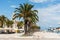 Seaside buildings and palm trees under the blue cloudy sky