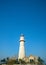 Seaside lighthouse on blue sky background, vertical composition, copy space