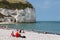 Seaside visitors sitting at beach near limestone cliffs Yport, France