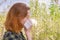 Season allergy to flowering plants pollen. Young woman with paper handkerchief in hand covering her nose in garden. Teen girl