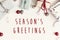 Season`s greetings text on modern christmas flat lay with orname