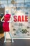 Season sale, black friday and shopping concept. One woman mannequins in red clothes on in store shop window. Sale sign with