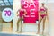 Season sale, black friday and shopping concept. Women`s clothing store showcase. Two woman mannequins in red swimsuits. Sale sign