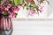 Seasonal bouquet of flowering apple trees in a vase. Pink apple blossoms in a ceramic vase on a wooden table. Shallow