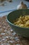 Seasoned rigatoni pasta in a green bowl on a burlap mesh with a garlic bulb in the background