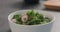 Seasoning fresh salad with radish, cucumber and herbs in white bowl