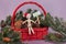 Seasons Greetings sign held by wooden doll wearing Santa hat sitting in red Christmas basket