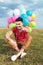 Seated casual man with balloons points at you