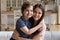 Seated on couch at home young mother embracing preschool son