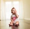 Seated little girl chewing on her fingers and looks up