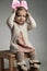 Seated little girl putting on a pink bow headband