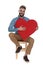 Seated student in jeans shirt holds hand on red heart