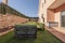 seating area of pallet sofas with green cushions next to a brick house with a garden and artificial grass floors