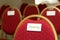 Seating chairs for guests at a wedding ceremony in the festive hall. Chairs upholstered in red cloth nameplate family