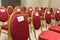 Seating chairs for guests at a wedding ceremony in the festive hall. Chairs upholstered in red cloth nameplate family