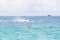 Seawater landscape with cargo ship on horizon and speedboat.