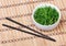Seaweed with sesame seeds with chopsticks in ceramic bowl on bamboo mat. Chuka salad.
