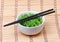 Seaweed with sesame seeds with chopsticks in ceramic bowl on bamboo mat. Chuka salad.