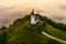Sebrelje, Slovenia - Aerial drone view of the beautiful hilltop church of St.Ivan Sv. Ivan Cerkev at sunrise with morning fog