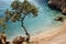 Secluded mediterranean beach with clear turquoise waters, trees, and rocky shoreline