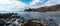 Secluded rocky cove on a wild mountainous coastline with rocks and tidal pools in the foreground