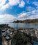 Secluded rocky cove on a wild mountainous coastline with rocks and tidal pools in the foreground