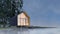 Secluded tiny house on the sandy shore of a lake with fog in a coniferous forest in cold cloudy lighting with warm light from the