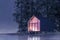 Secluded tiny house on the sandy shore of a lake with fog in a coniferous forest in the cold night light and with warm light from