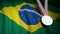 Second place medal against of waving Brazil flag