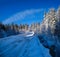 Secondary countryside alpine road to remote mountain hamlet through snowy fir forest, snow drifts and wood fence on wayside