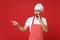Secret chef cook baker man in apron toque chefs hat posing isolated on red background. Cooking food concept. Mock up