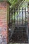 Secret garden pathway. Iron gate with padlock at walled garden entrance