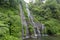 Secret jungle waterfall cascade in tropical rainforest with rock