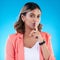 Secret, portrait and woman with finger on lips in studio, blue background and privacy sign. Young female model, silence