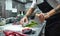 Secret recipe. Cropped photo of chef`s hands with tattoos cutting dough on the kitchen table with flour for homemade