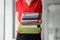 Secretary in red blouse holds stack of folders in hands