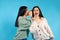 Secrets and emotion. Smiling twin women wearing fashion clothes on blue background with empty space