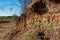 Section of a part of a slope with layers of variegated clay covered with a layer of soil on top