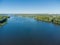 Section of wide plain river with forested banks, aerial view