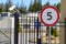 Secure entrance to the parking territory, surrounded by steel fence. Near the gate there is a video camera and a sign limiting the