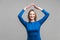 Secured life, insurance concept. Portrait of cheerful woman showing home roof gesture.  on gray background