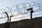 Security camera behind barbed wire fence on the wall, prison, security, crime or illegal immigration concept, blue sky