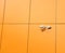 Security camera mounted on modern building wall finished with orange panels horizontal view closeup