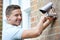 Security Consultant Fitting Security Camera To House Wall