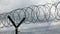 Security fence with a barbed wire with grey sky.