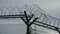 Security fence with a barbed wire with grey sky. Fence with a barbed wire.